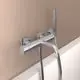 Badearmatur von Ideal Standard in Chrom-Ausführung, montiert an einer hellen Wand, mit Handbrause und Wassertülle.